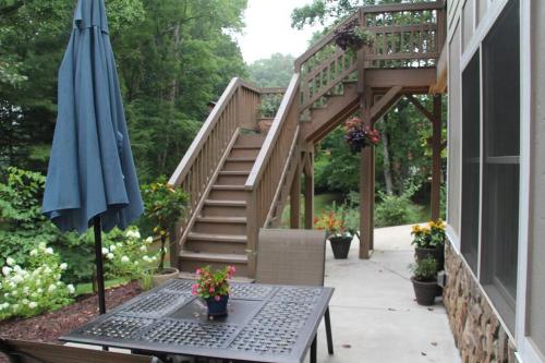 a patio with an umbrella and a table and stairs at Bluebirds Nest 10 Min to AVL Biltmore hot tub cont bkfst sparkling water in Asheville