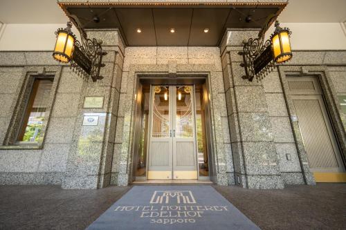 a front door of a building with a sign on the ground at Hotel Monterey Edelhof Sapporo in Sapporo
