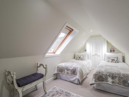 a attic bedroom with two beds and a window at Lydia Cottage - Cromarty in Cromarty