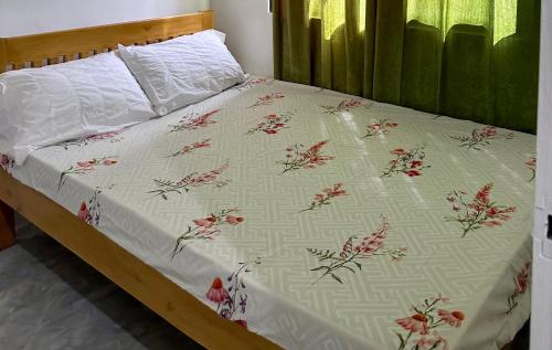 a bed with a white blanket with red flowers on it at My Lovely Apartment in Dipolog