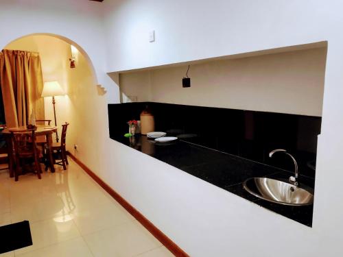 uma cozinha com um lavatório e uma mesa em Blossomwell Bungalow em Nuwara Eliya