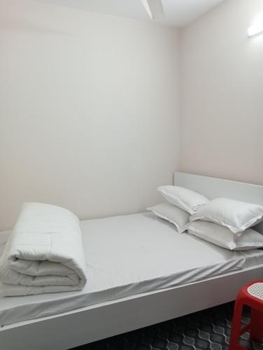 a bed with white sheets and pillows on it at Hotel In Need - Near to the US France Italy Saudi Embassy and Airport in Dhaka