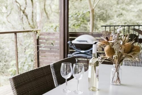 una mesa con dos copas y una botella de vino en "On Burgum Pond" Cottages, en Maleny