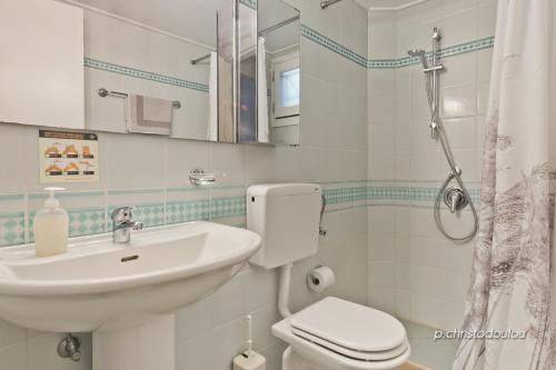 a white bathroom with a sink and a toilet at Rigò Apartments in Kyra Panagia