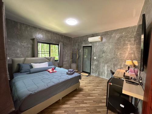a bedroom with a bed and a desk in it at บ้านสวนริมธาร โฮมสเตย์ ท้ายเหมือง พังงา 