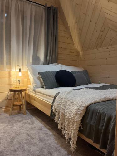 ein Schlafzimmer mit einem Bett und einem Tisch mit einer Lampe in der Unterkunft Domki WIDOKÓWKA in Bukowina Tatrzańska