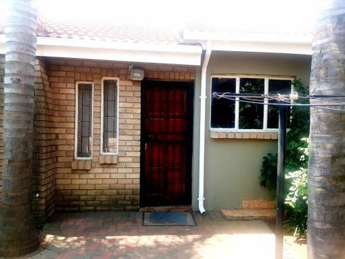 a brick house with a red door and a window at Gae la boroko cabin in Brakpan