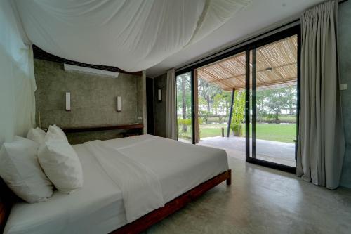 a bedroom with a white bed with a large window at Costa Lanta - Adult Only in Ko Lanta