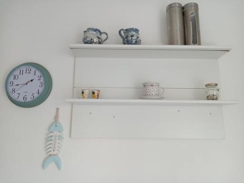a clock hanging on a wall with shelves at appartamento incantevole a Ospedaletti(Sanremo) in Ospedaletti