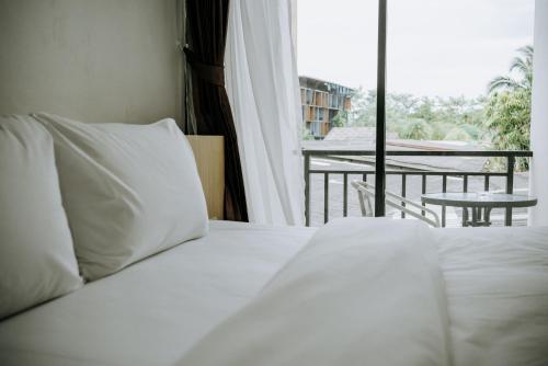 a bed with white sheets and a view of a balcony at Circle Inn Ao Nam Mao in Ao Nam Mao