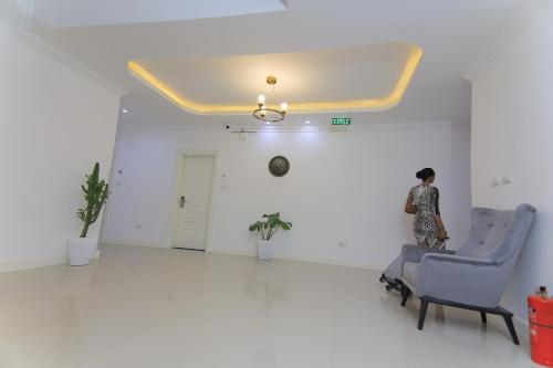 a woman standing in a white room with a blue chair at Zemilo Hotel Apartment in Addis Ababa