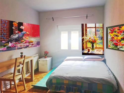 安静双人房 في مدريد: غرفة نوم بها سرير ولوحات على الحائط