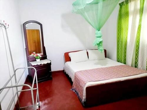 a small bedroom with a bed and a mirror at Mountain Paradise Homestay in Bandarawela