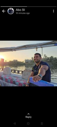 a man sitting on a boat in the water at Aswan Felucca sailing boat and Hotel in Aswan