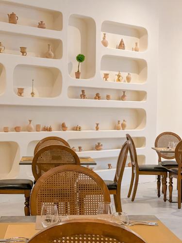 a dining room with chairs and shelves of pottery at Western Hotel Liwa in Liwa