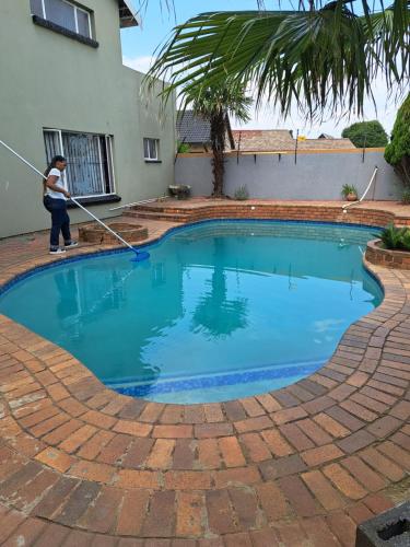 a woman is cleaning a swimming pool with a hose at Gae la boroko @legodi's in Brakpan