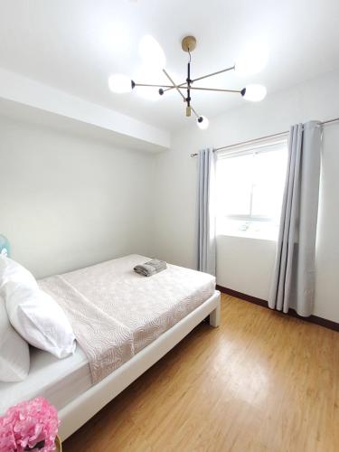 um quarto branco com uma cama e uma janela em MesaVerte Residence By Ms German em Cagayan de Oro