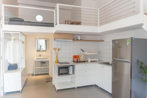 a kitchen with white cabinets and a stainless steel refrigerator at M Village Living Lê Văn Sỹ in Ho Chi Minh City