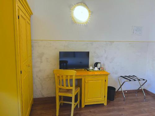 una scrivania gialla con televisore e sedia di Hotel Duca D'Aosta a Firenze