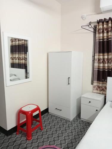 a bedroom with a red stool and a white cabinet at Hotel In Need - Near to the US France Italy Saudi Embassy and Airport in Dhaka