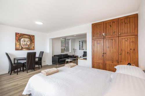 a bedroom with a white bed and a dining room at Apartment 201 - Fremantle studio apartment with ocean and harbour views in Fremantle