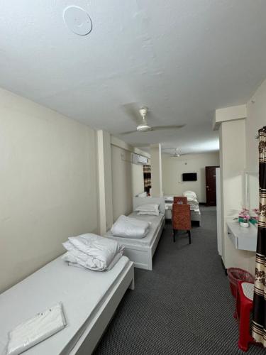 a room with three beds and a chair in it at Hotel In Need - Near to the US France Italy Saudi Embassy and Airport in Dhaka