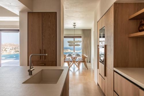 a kitchen with a view of the ocean and a dining room at The Skyvilla Mykonos - A Landmark Property with Breathtaking Views of the Psarou bay in Mikonos