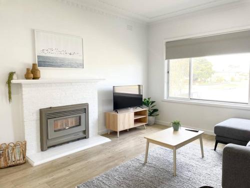 Il comprend un salon avec une cheminée et une télévision. dans l'établissement 83 Appin - Newly renovated house, à Wangaratta