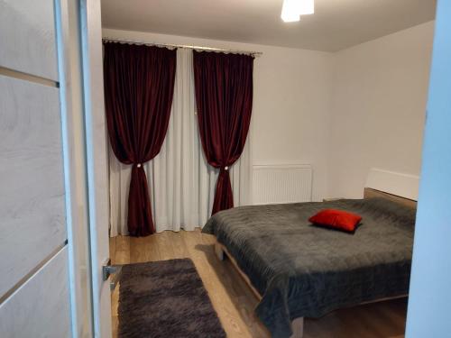 1 dormitorio con 1 cama y cortinas rojas en Casa Ioana en Târgu Mureș