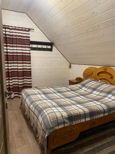 ein Schlafzimmer mit einem Holzbett im Dachgeschoss in der Unterkunft ЕКО-котедж in Werchowyna
