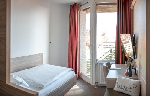 ヘレンベルクにあるHotel am Schlossbergのベッドルーム1室(ベッド1台、デスク、窓付)