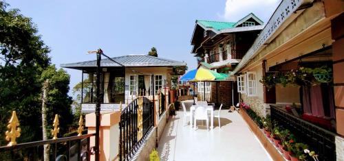 uma varanda de um edifício com mesas e guarda-sóis em Pinewood Homestay em Darjeeling