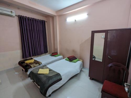 two beds in a small room with a mirror at Saikia Nest the Home-stay in Guwahati