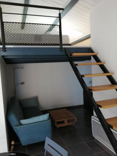 Cette chambre mansardée dispose d'un escalier et d'un canapé. dans l'établissement Joli studio au calme, à Grand-Village-Plage