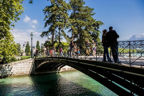 um grupo de pessoas em pé em uma ponte sobre a água em chez Caroline em Annecy