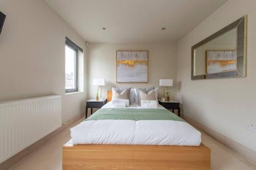a bedroom with a large bed and two windows at Elegant 1-BR Retreat in Ilford Centre in Ilford