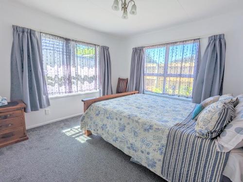 a bedroom with a bed and two large windows at Springfield Bliss in Rotorua