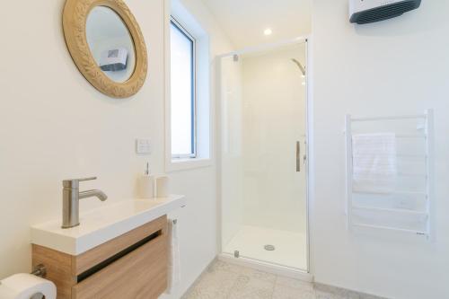 a white bathroom with a sink and a shower at The Mayflower Cottage in Te Anau