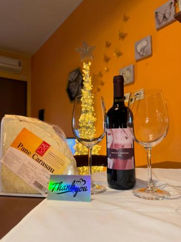 a bottle of wine and two glasses on a table at ButterflyHouse in Monserrato
