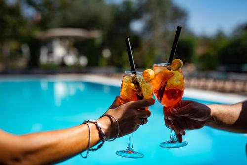 two people holding up two cocktails in front of a pool at Hotel Villa Rizzo Resort and Spa in San Cipriano Picentino