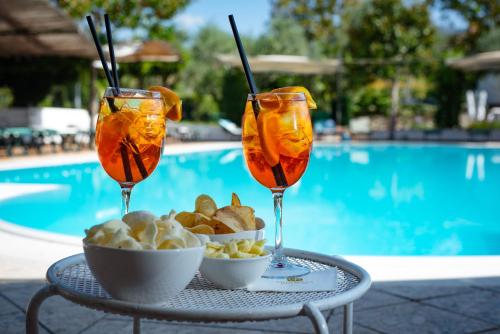 two wine glasses with food on a table next to a pool at Hotel Villa Rizzo Resort and Spa in San Cipriano Picentino