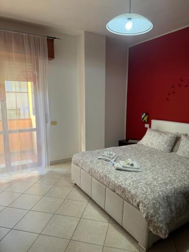a bedroom with a large bed with a red wall at ButterflyHouse in Monserrato