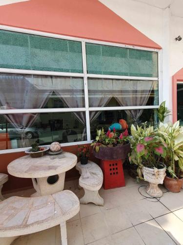 a patio with tables and potted plants in front of a building at City Inn Udonthani in Udon Thani