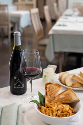 a table with a plate of food and a glass of wine at Hotel Roma in Palmanova