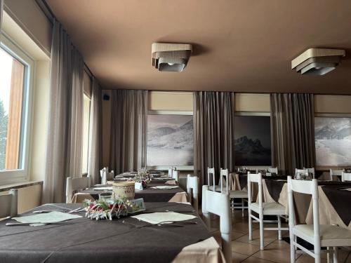 uma sala de jantar com mesas longas e cadeiras em Hotel Rododendro Val di Fassa em Campitello di Fassa