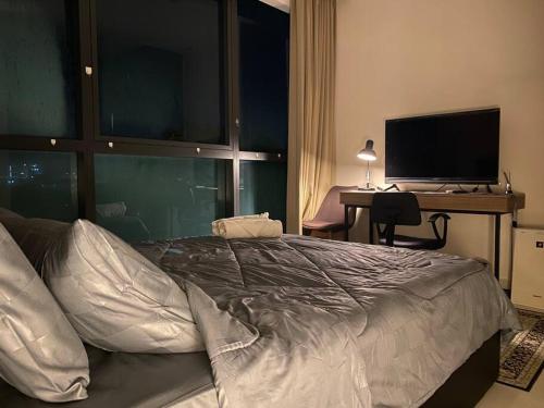 Un dormitorio con una cama y un escritorio con televisión. en Malina Cozy Suite 3.0 @Kozi Square, en Kuching