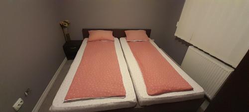 VulcanにあるDALLAS Apartament 31のピンクのシーツと枕が備わる小さな部屋のベッド1台分です。