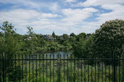 a fence in front of a river with a house at Fabulous River View - Brand New House In Hamilton in Hamilton