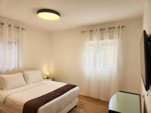 a white bedroom with a bed and a window at arie apartment in Eilat