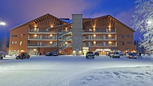 a large building in a parking lot in the snow at Apartments Tähtitahko in Tahkovuori